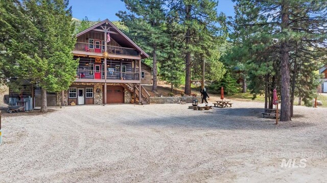 1010 N Hidden Pine Rd, Pine, ID 83647 - view of front of property with a garage, stone siding, dirt driveway, stairs, and a wooden deck