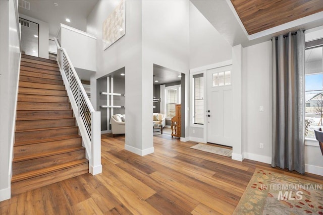 foyer with hardwood / wood-style floors, wooden ceiling, and a high ceiling