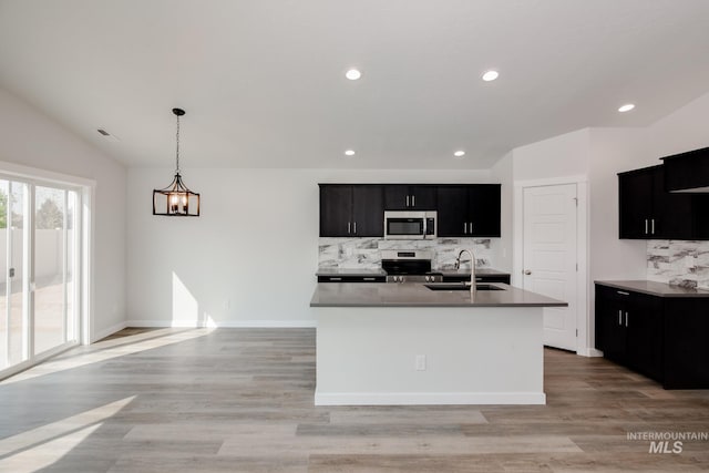 kitchen featuring lofted ceiling, a center island with sink, pendant lighting, sink, and stainless steel appliances