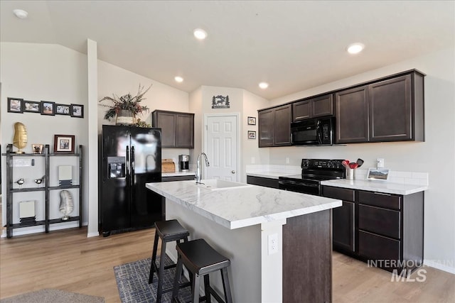 kitchen featuring lofted ceiling, black appliances, sink, an island with sink, and dark brown cabinetry