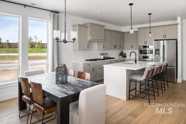 2005 W Freya Ct, Eagle, ID 83616 - kitchen featuring gray cabinets, appliances with stainless steel finishes, a sink, a breakfast bar area, and light countertops