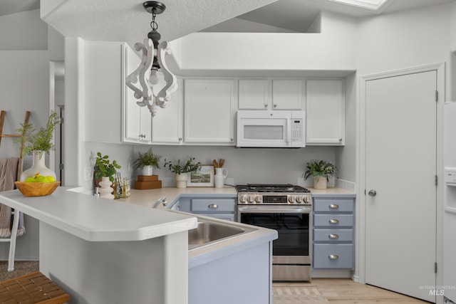 kitchen featuring a breakfast bar, pendant lighting, white cabinetry, kitchen peninsula, and stainless steel gas range oven