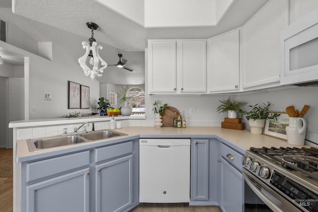 kitchen with sink, white appliances, hanging light fixtures, white cabinets, and kitchen peninsula