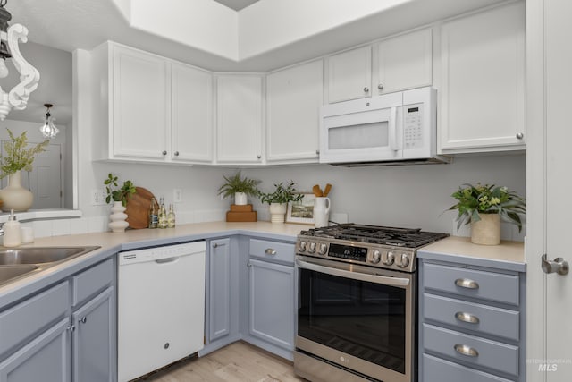 kitchen featuring gray cabinets, decorative light fixtures, white cabinets, white appliances, and light hardwood / wood-style flooring