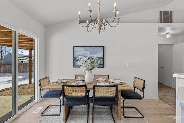 dining space with vaulted ceiling, a chandelier, and light hardwood / wood-style flooring