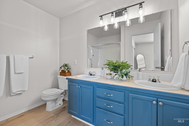 bathroom with wood-type flooring, toilet, vanity, and a shower with shower door