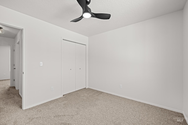 unfurnished bedroom featuring ceiling fan, light colored carpet, a closet, and a textured ceiling