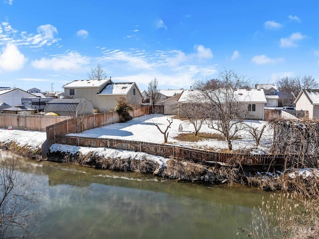 snow covered back of property featuring a water view