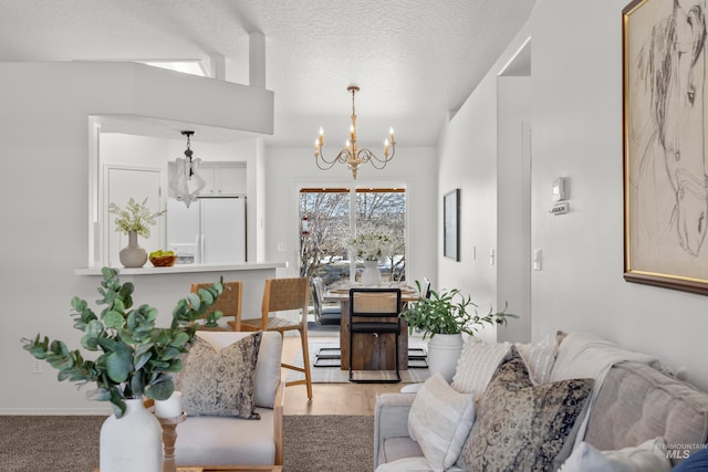 living room featuring baseboard heating, a notable chandelier, a textured ceiling, and light hardwood / wood-style floors