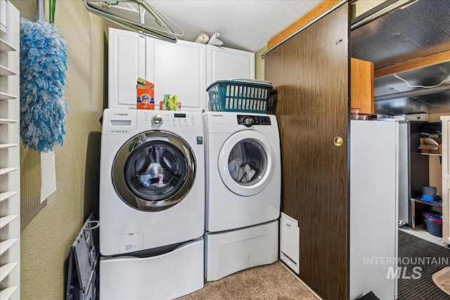 clothes washing area featuring cabinet space, a textured ceiling, and washer and dryer