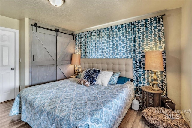 3976 Ranch Ln, Emmett, ID 83617 - bedroom with a barn door, wood finished floors, and a textured ceiling