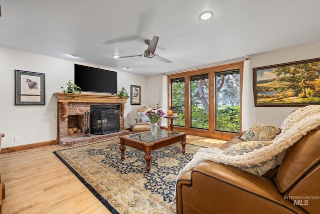 living room featuring a fireplace, light hardwood / wood-style flooring, and ceiling fan