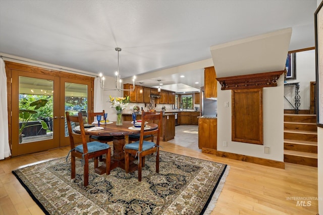 dining area featuring french doors, a notable chandelier, and light wood-type flooring