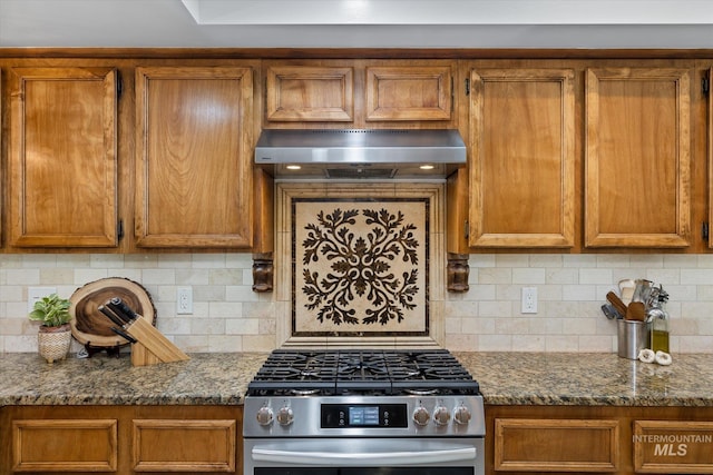 kitchen featuring tasteful backsplash, dark stone countertops, exhaust hood, and stainless steel gas range oven