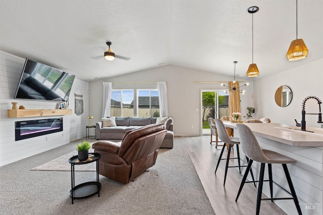 8408 E Dutchman St, Nampa, ID 83687 - living room featuring ceiling fan with notable chandelier, lofted ceiling, a glass covered fireplace, light carpet, and light wood-style flooring