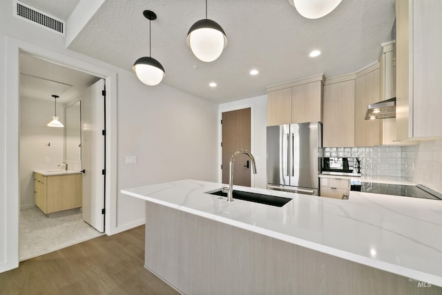kitchen with visible vents, wood finished floors, a sink, freestanding refrigerator, and a peninsula