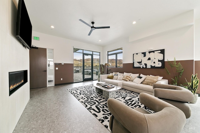 living room featuring a glass covered fireplace, speckled floor, a ceiling fan, baseboards, and recessed lighting
