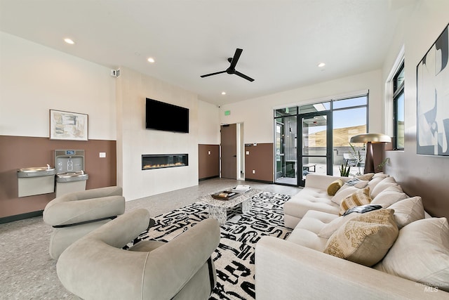 living room with a large fireplace, ceiling fan, and recessed lighting