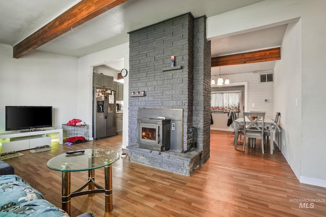 909 Victoria Ave, Fruitland, ID 83619 - living area featuring beamed ceiling, light wood-style floors, a chandelier, baseboards, and a warm lit fireplace