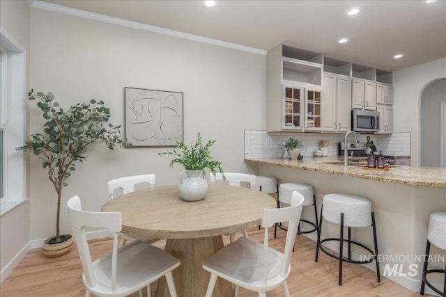 4975 N Morninggale Way, Boise, ID 83713 - kitchen featuring stainless steel microwave, a breakfast bar, decorative backsplash, light wood-style floors, and recessed lighting