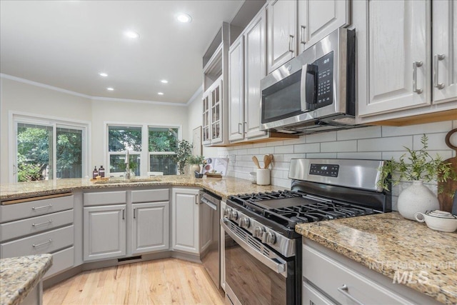 4975 N Morninggale Way, Boise, ID 83713 - kitchen featuring appliances with stainless steel finishes, crown molding, light wood-style flooring, tasteful backsplash, and light stone counters