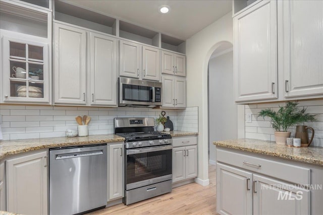 4975 N Morninggale Way, Boise, ID 83713 - kitchen featuring stainless steel appliances, glass insert cabinets, light wood-style floors, decorative backsplash, and recessed lighting