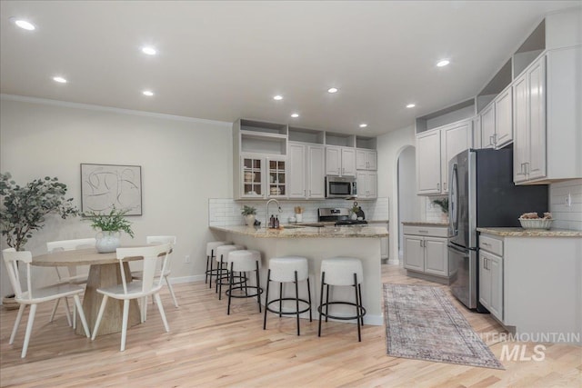 4975 N Morninggale Way, Boise, ID 83713 - kitchen featuring appliances with stainless steel finishes, a peninsula, a breakfast bar, tasteful backsplash, and recessed lighting