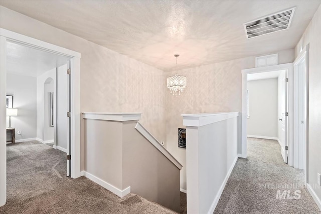hallway featuring an upstairs landing, carpet floors, a chandelier, and baseboards