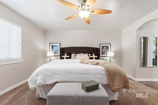 carpeted bedroom with arched walkways, baseboards, and ceiling fan