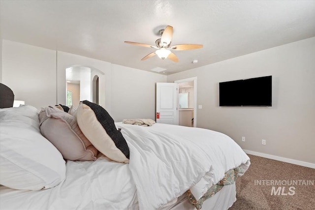 carpeted bedroom with arched walkways, baseboards, and a ceiling fan