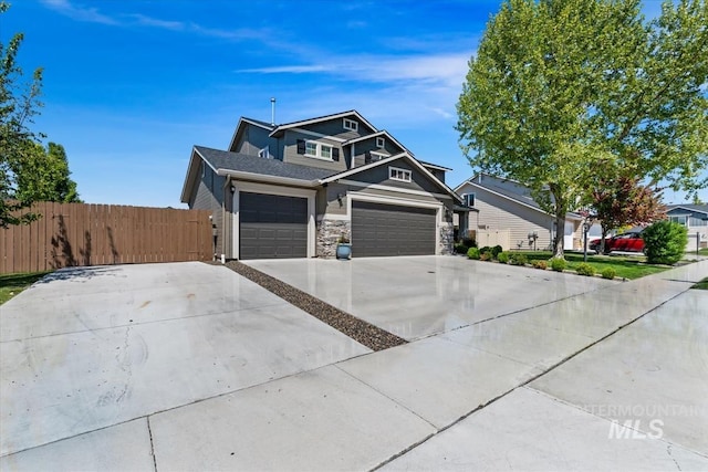 view of front facade with fence, driveway, stone siding, and an attached garage