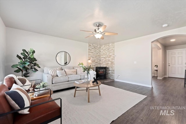 living room with arched walkways, ceiling fan, dark wood finished floors, and baseboards