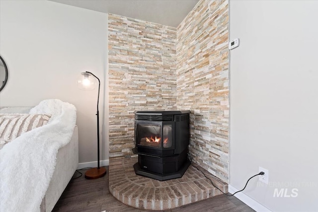 detailed view of wood finished floors, a wood stove, and baseboards