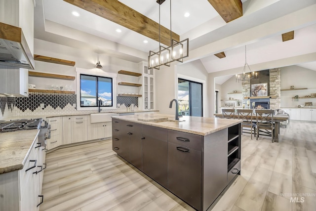 1580 Clear Creek Loop, Twin Falls, ID 83301 - kitchen with open shelves, open floor plan, tasteful backsplash, light wood finished floors, and a kitchen island with sink