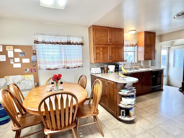 kitchen with decorative backsplash, brown cabinetry, dishwasher, light countertops, and a sink