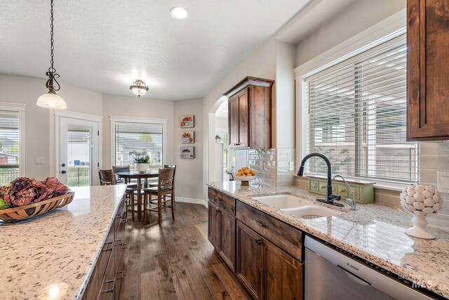1175 N Champions Pl, Eagle, ID 83616 - kitchen with dark wood-style floors, a sink, dishwasher, arched walkways, and pendant lighting