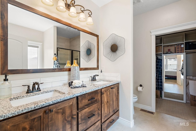 bathroom featuring vanity, toilet, a shower with shower door, and a textured ceiling