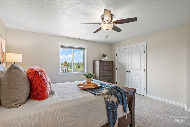 bedroom with a closet, a textured ceiling, ceiling fan, and carpet floors