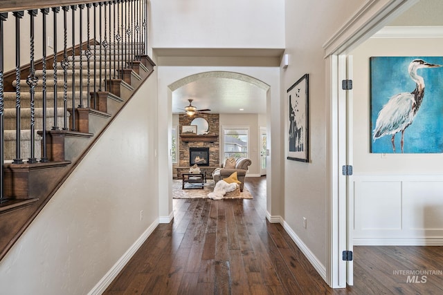 entryway featuring crown molding, ceiling fan, dark hardwood / wood-style flooring, and a fireplace