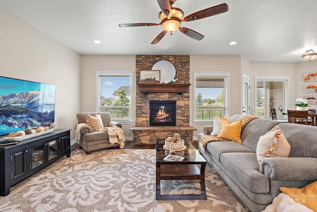 living room with ceiling fan, a fireplace, wood-type flooring, and a textured ceiling