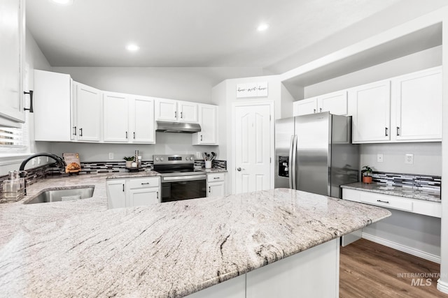 kitchen with appliances with stainless steel finishes, a sink, under cabinet range hood, vaulted ceiling, and light stone counters