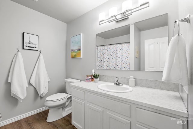 full bath with wood finished floors, toilet, vanity, and baseboards
