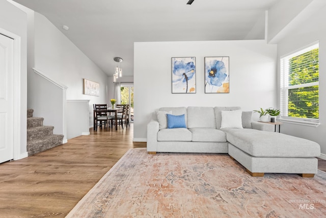 living area featuring wood finished floors, stairway, vaulted ceiling, baseboards, and a ceiling fan