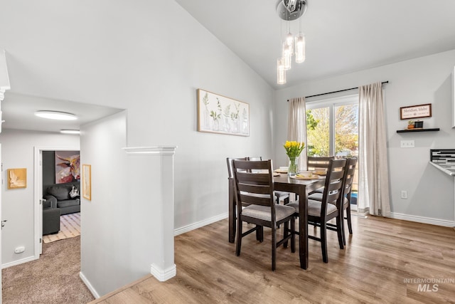 dining space with vaulted ceiling, baseboards, and wood finished floors
