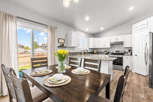 dining space with vaulted ceiling, light wood-style flooring, healthy amount of natural light, and recessed lighting