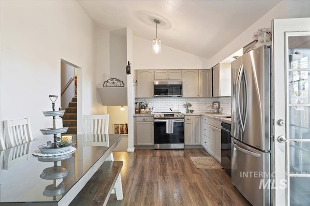 kitchen with appliances with stainless steel finishes, vaulted ceiling, dark wood-style floors, tasteful backsplash, and light countertops