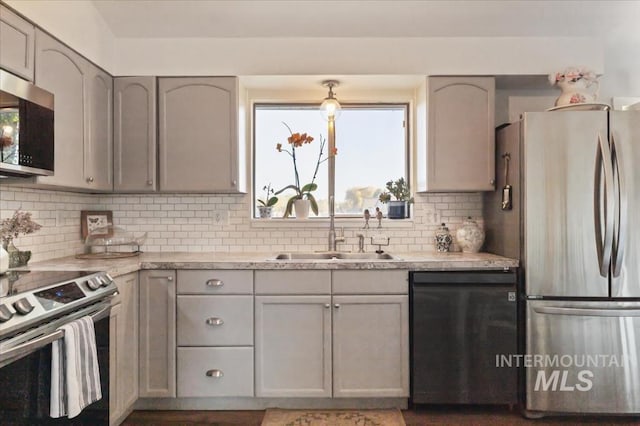 kitchen featuring stainless steel appliances, a sink, gray cabinetry, light countertops, and tasteful backsplash