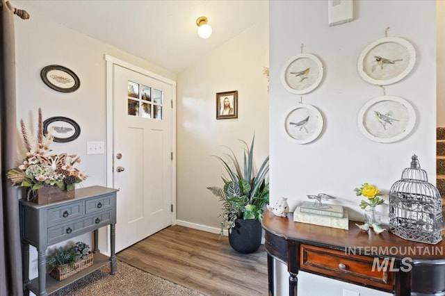 entrance foyer with baseboards, lofted ceiling, and wood finished floors