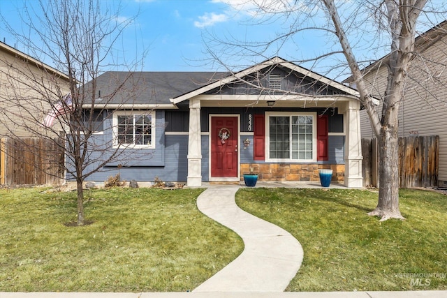 view of front of house featuring stone siding, a front yard, and fence