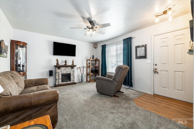 carpeted living area with ceiling fan, a fireplace, and wood finished floors